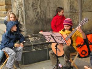 group of four kids wearing colorful clothes and one playing guitar