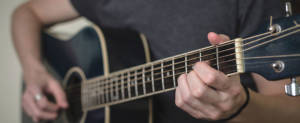 close up of hands playing a black guitar